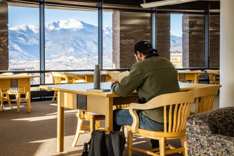 Student sitting in the El Kraemer library working at a desk 